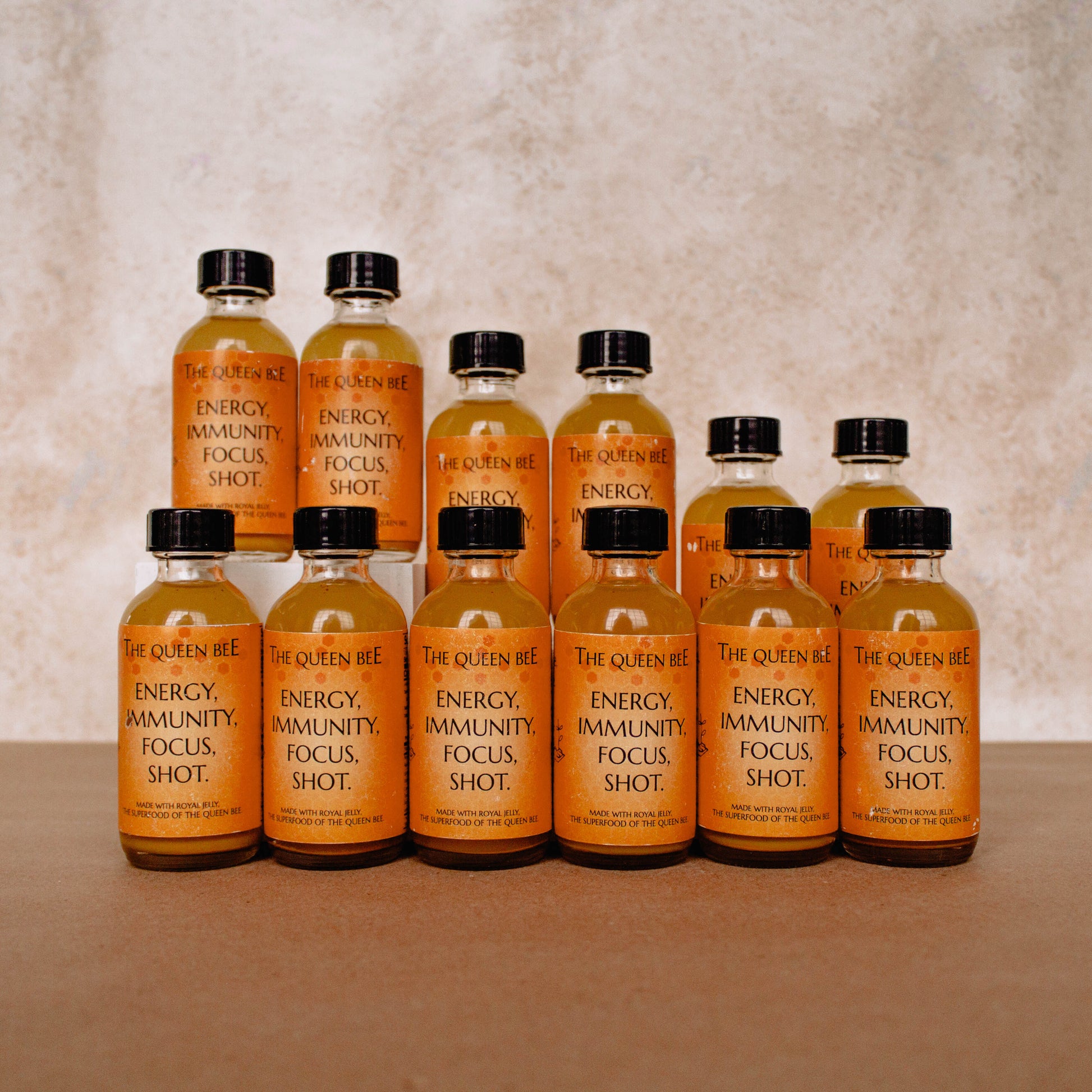 Photo of our 12 pack wellness shot, expertly formulated with just 6 ingredients sourced furor 4 continents around the world. Freshly juiced ginger from Peru, turmeric from India, lemons from Florida, cayenne from Japan, royal jelly from the Amazon rainforest, and buckwheat honey straight from our local bee farms.